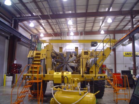 1966 International School Bus - This yellow heavy machinery is in a workshop, showing its engine and fan components.