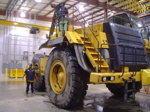 1966 International School Bus - A massive yellow mining truck is shown with two workers nearby, highlighting its immense scale.