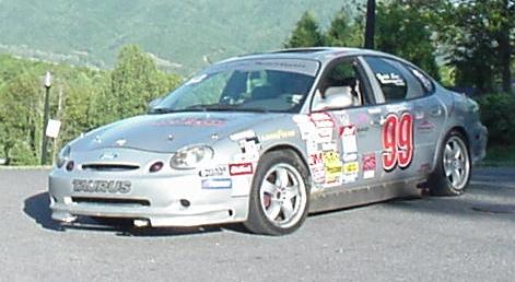 1991 Ford Taurus - This silver race car, identified as a Taurus, appears to be from the 1996 model year based on its body style.