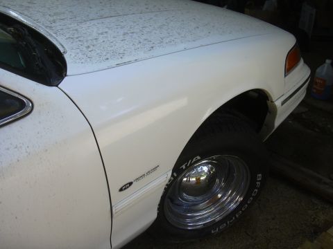 1997 Ford Crown Victoria - Close-up of a white 1997 Ford Crown Victoria showing the front fender and wheel.