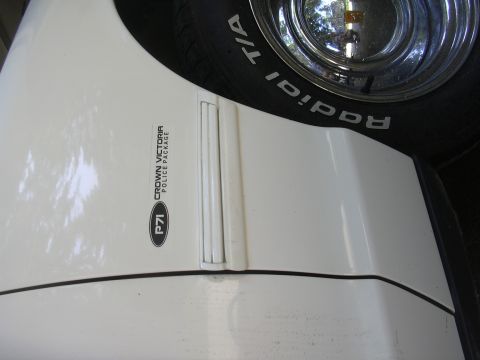 1997 Ford Crown Victoria - Close-up of a white Ford Crown Victoria police car fender, showing the P71 badge and a portion of the tire and wheel.
