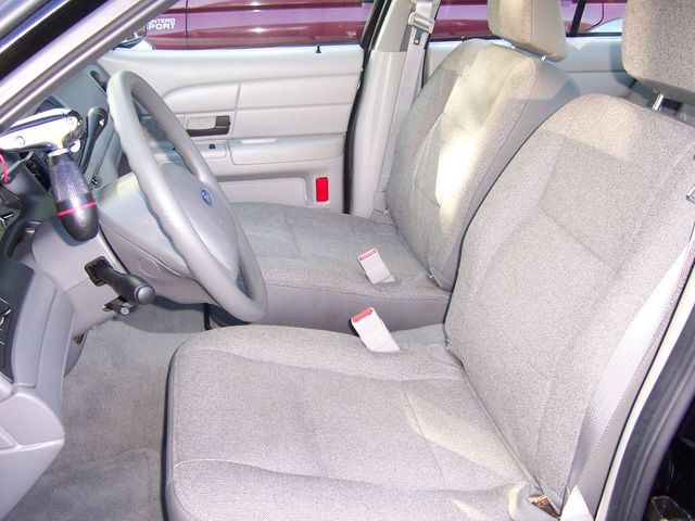 Car interior showing front seats, steering wheel, and dashboard. A red light is visible on the door panel