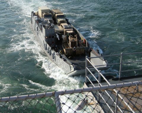 1986 Ford Bronco - Military landing craft transports trucks and construction equipment across the water.