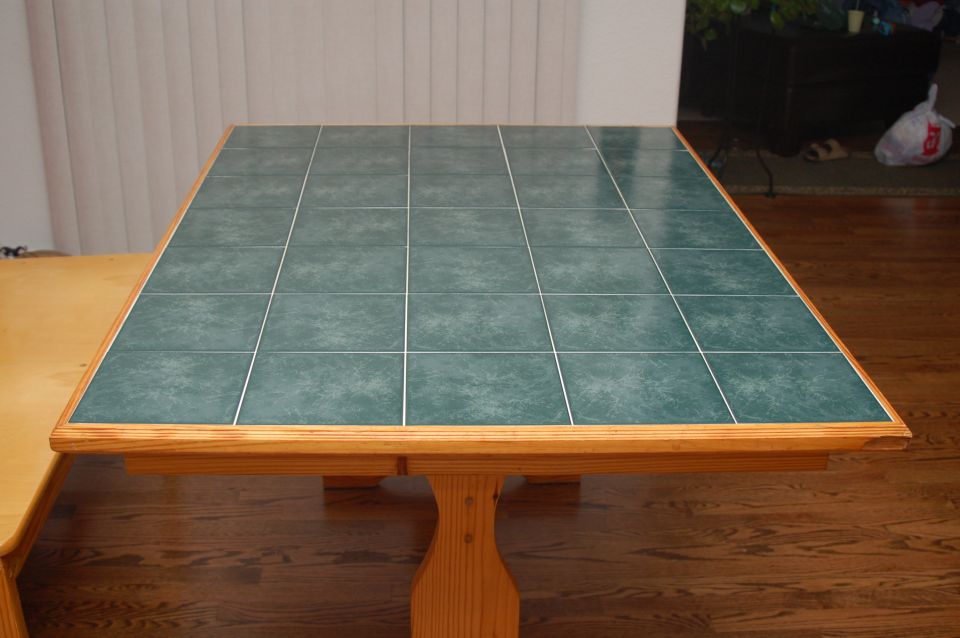 Green tile-topped pine dining table and bench on a hardwood floor