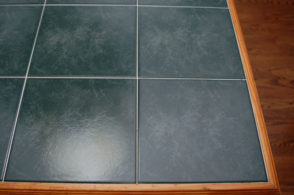 Green marbled ceramic tile floor meeting hardwood at a wood transition strip