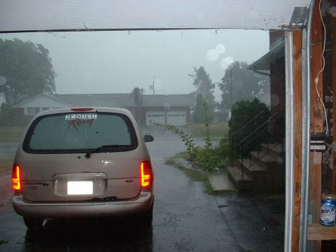 1978 Ford Mustang II - A Ford Windstar minivan is parked outside during a heavy rainstorm, with a Roush Racing sticker on its rear window.