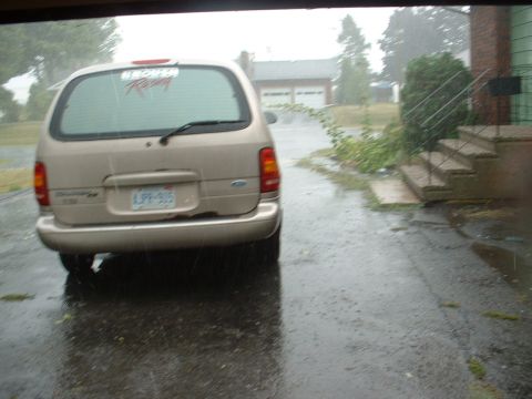 1978 Ford Mustang II - Minivan parked on a wet driveway during a rain shower.
