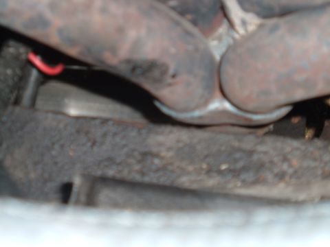 1990 Ford Ranger - Close-up view of rusted exhaust manifold pipes and undercarriage components.