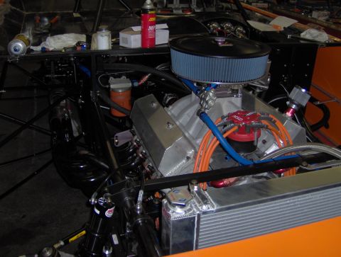 1978 Ford Bronco - Close-up view of a V8 engine, an air filter, radiator, and orange body panels, likely in a race car.
