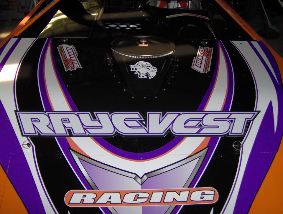 Close-up of a racing car's hood with 'RAYE VEST RACING' graphics. Also has a lion logo and sponsor decals