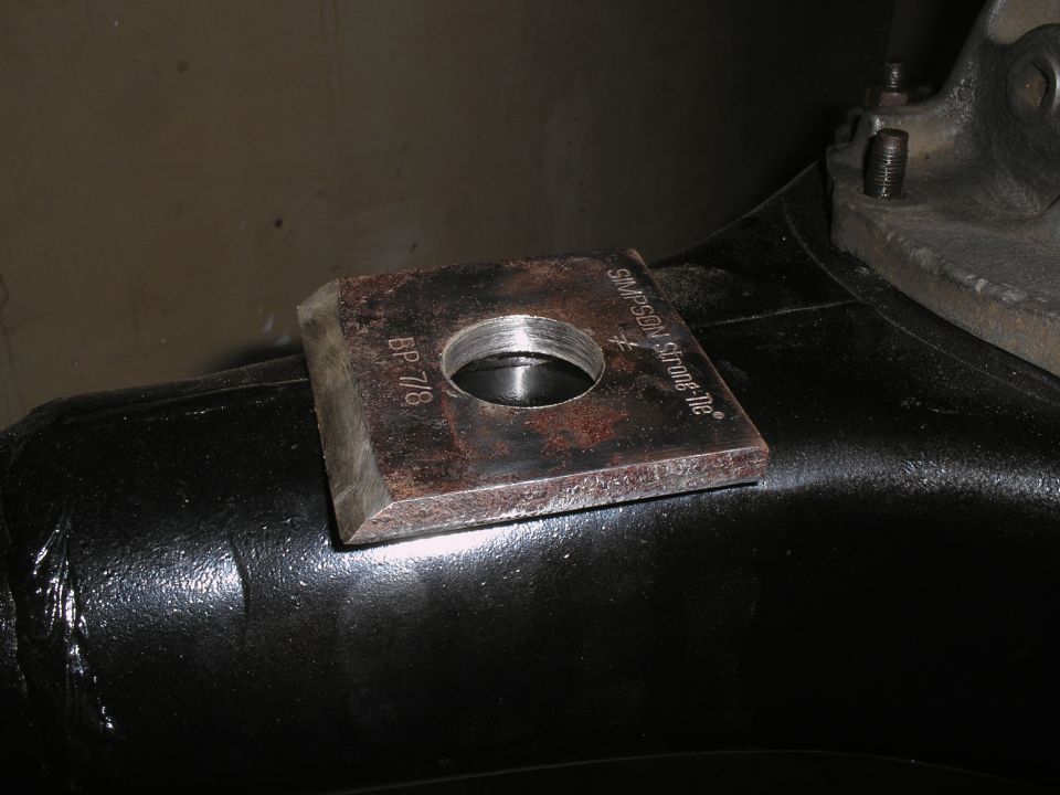 Square metal plate with threaded hole, marked "BP 7/8" and "SIMPSON Strong-Tie", attached to black suspension component