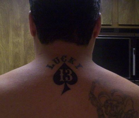 1989 Ford Bronco - Close-up of the back of a person's neck and upper back showing a black spade tattoo with the word LUCKY arched above and the number 13 insi…