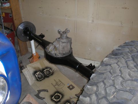 1990 Ford Bronco - Rear axle assembly, likely for a 4x4, sits on an engine stand next to a tire.