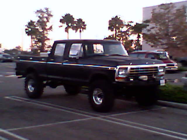 Black Ford F-Series pickup truck parked in a lot, with another vehicle behind it