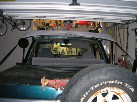 1995 Ford Bronco - Rear view of a teal Ford Bronco with its soft top removed, parked inside a garage.