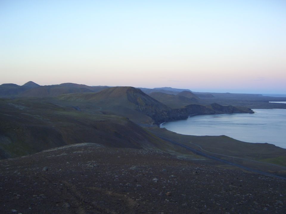 Dusk over volcanic coastal hills with a bay and winding road