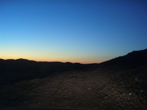 1996 Ford Bronco - A desolate landscape with rolling hills and a gravelly foreground under a twilight sky.