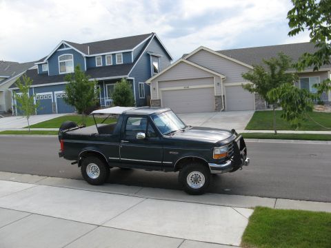 1995 Ford Bronco - This 1995 Ford Bronco features a removable white soft top, offering an open-air driving experience.