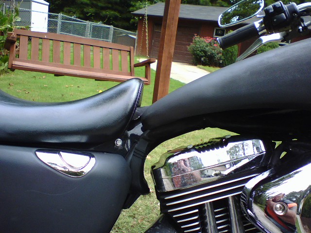 Close-up of a 2006 Harley-Davidson Sportster Custom engine and seat, with a wooden swing in the background