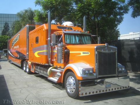 1968 Ford Mustang - A bright orange semi-truck with a matching trailer is parked on a paved surface.