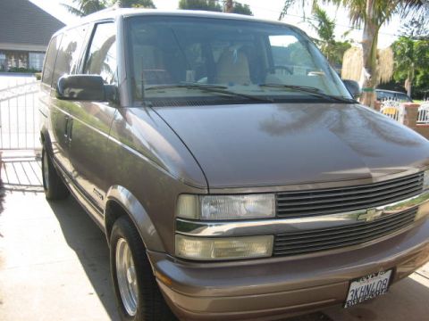 1968 Ford Mustang - A brown Chevrolet Astro van is parked in a driveway on a sunny day, with palm trees in the background.