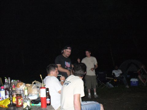 1991 Ford Probe - People gathered around a table at a campsite at night, with various items on the table.