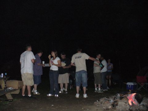 1991 Ford Probe - A group of people are gathered outdoors at night, with a campfire burning in the foreground.