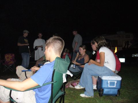 1991 Ford Probe - A group of friends enjoy a nighttime gathering outdoors, with a trailer and vehicle visible in the background.