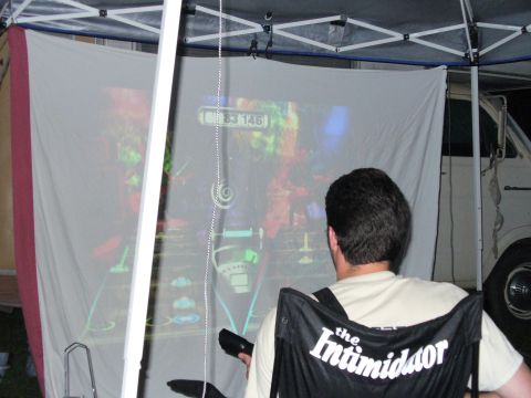 1991 Ford Probe - A man plays a video game projected onto a screen, with a white van partially visible in the background.