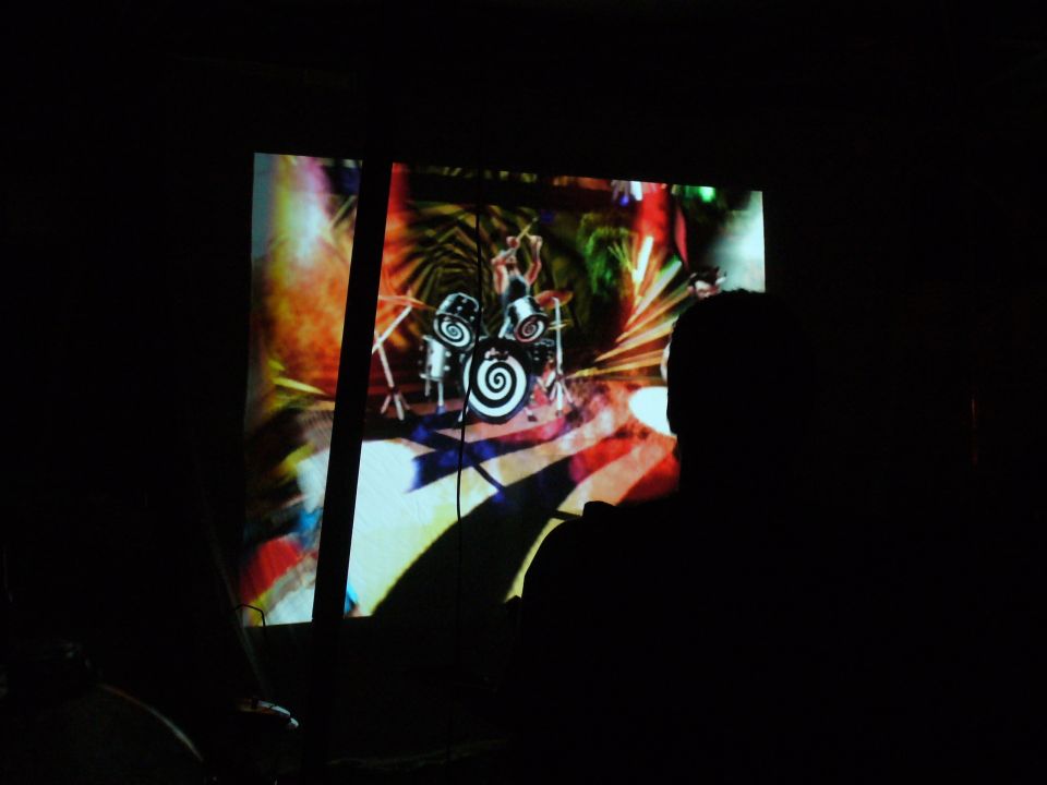 Person watching a projection of a drummer playing a drum set
