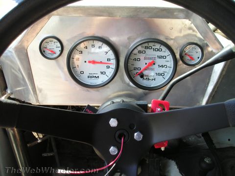 1990 Ford Bronco - Auto Meter tachometer and speedometer mounted in an aluminum panel behind a black flat race steering wheel.