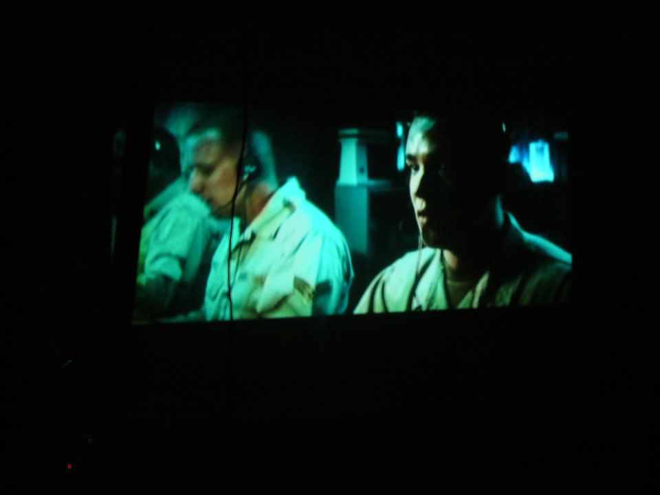 Two men wearing headsets watch a screen in a dark room; SUPERMOTORS.NET logo visible