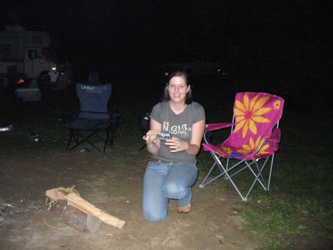 1991 Ford Probe - A woman kneels in front of a campsite, holding a camera, with a camper van visible in the dark background.