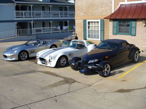 1995 Ford Thunderbird - Three distinct sports cars are parked side-by-side in an outdoor lot.