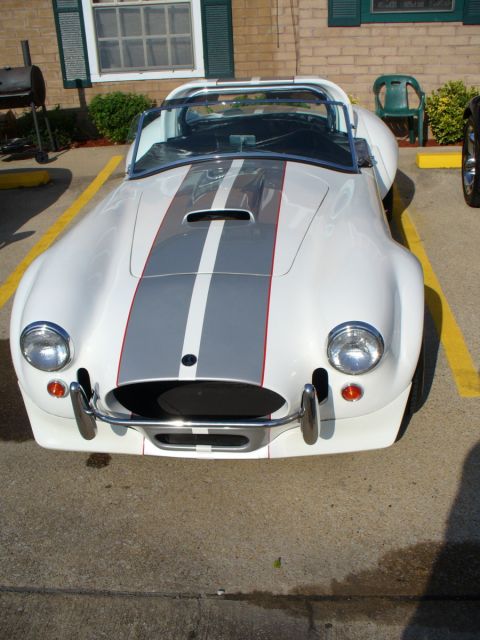 1995 Ford Thunderbird - A white AC Cobra replica is parked in a parking lot, showing its distinctive racing stripes.