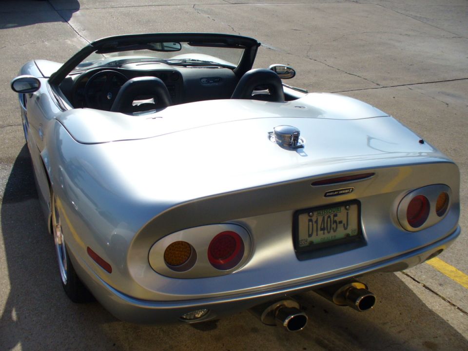 Silver convertible sports car rear view with dual exhaust and custom license plate