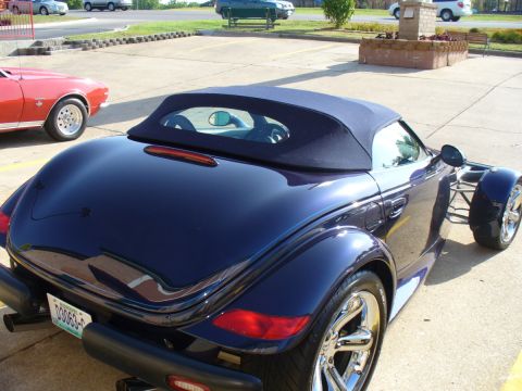 1995 Ford Thunderbird - A dark blue convertible is parked next to a red classic car in a lot.
