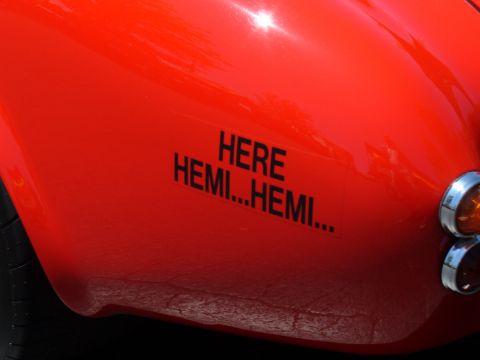 1995 Ford Thunderbird - A close-up of a red car's fender displays black lettering that reads 'HERE HEMI...HEMI...' next to a turn signal.