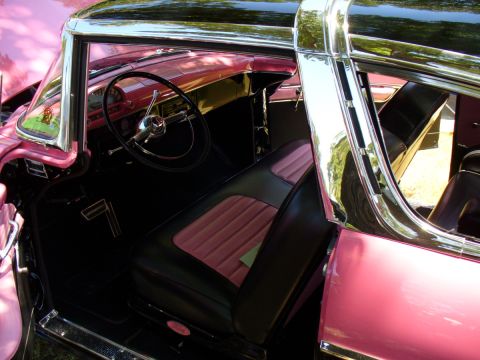 1995 Ford Thunderbird - Interior of a classic car with two-tone pink and black seats and a chrome steering wheel.
