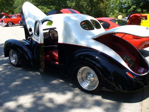 1995 Ford Thunderbird - A custom hot rod with its doors, hood, and trunk open is displayed at a car show, with other vehicles in the background.