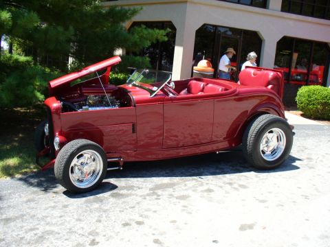 1995 Ford Thunderbird - A custom red hot rod convertible is displayed with its hood open, revealing the engine compartment.