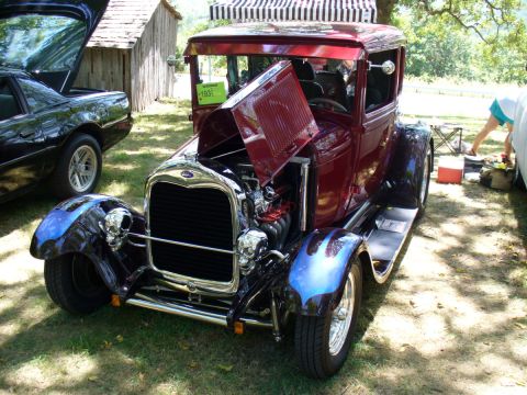1995 Ford Thunderbird - Customized 1931 Ford hot rod with skull accents and flame detailing on the fenders is displayed at a car show.