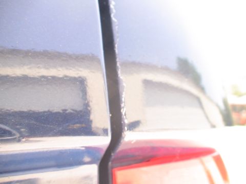 1993 Ford C-350 (Centurion Conversions) - Close-up of a dark blue vehicle's rear section, showing a taillight and body panel reflection.