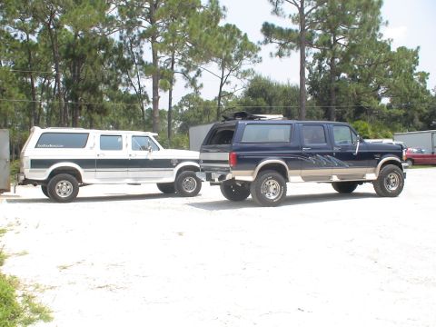 1993 Ford C-350 (Centurion Conversions) - Two Ford C-350 Centurion Conversion SUVs are parked in a gravel lot. The white SUV is on the left, and the blue SUV is on the right.