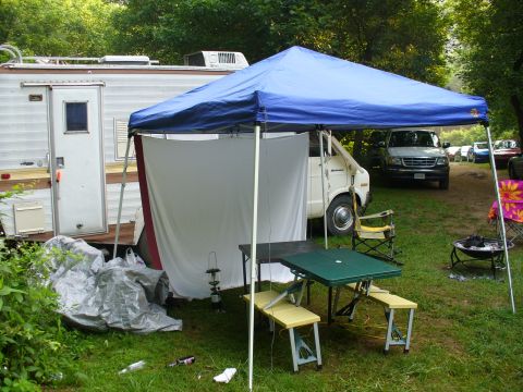 1991 Ford Probe - A campsite scene a camper, a van, and picnic area with other vehicles parked nearby.