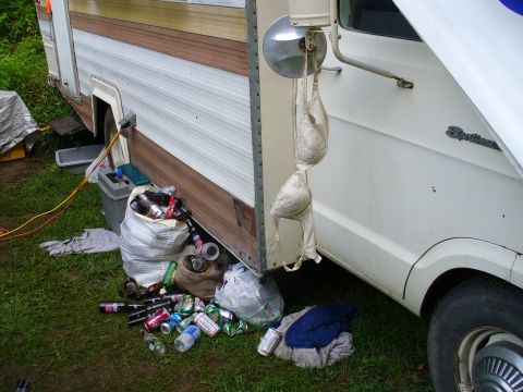 1991 Ford Probe - A white RV is parked with trash and debris scattered around it, including a bra hanging from the side mirror.