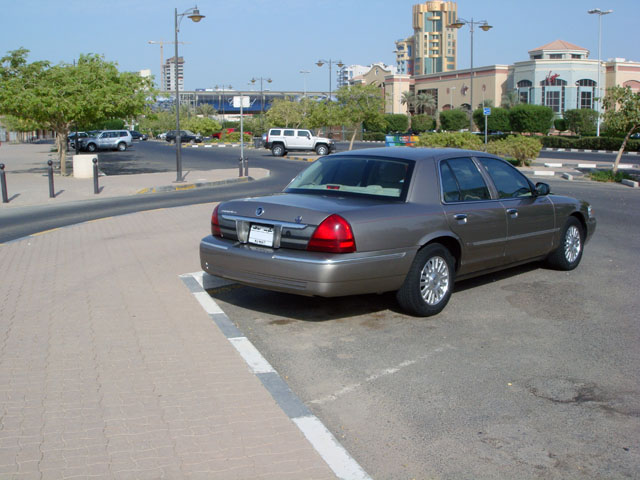 Tan four-door sedan viewed from rear 3/4 in a parking lot