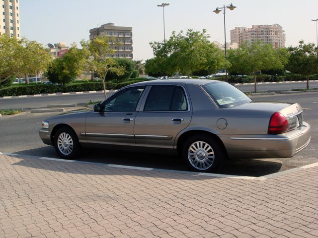 Tan Mercury Grand Marquis parked on a brick-patterned sidewalk