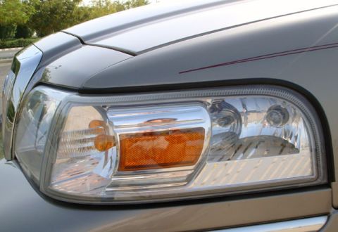 2007 Mercury Grand Marquis - The front passenger side headlight assembly of a 2007 Mercury Grand Marquis is shown with a portion of the chrome grille.