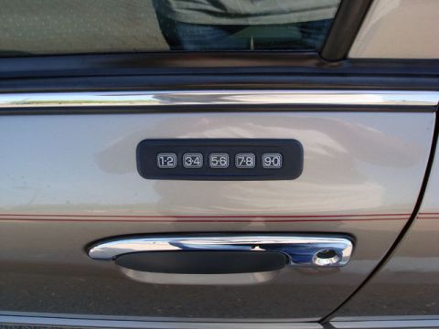 2007 Mercury Grand Marquis - Close-up of a five-button keyless-entry keypad (1·2, 3·4, 5·6, 7·8, 9·0) mounted on the tan/champagne driver's door above a chrome door han…